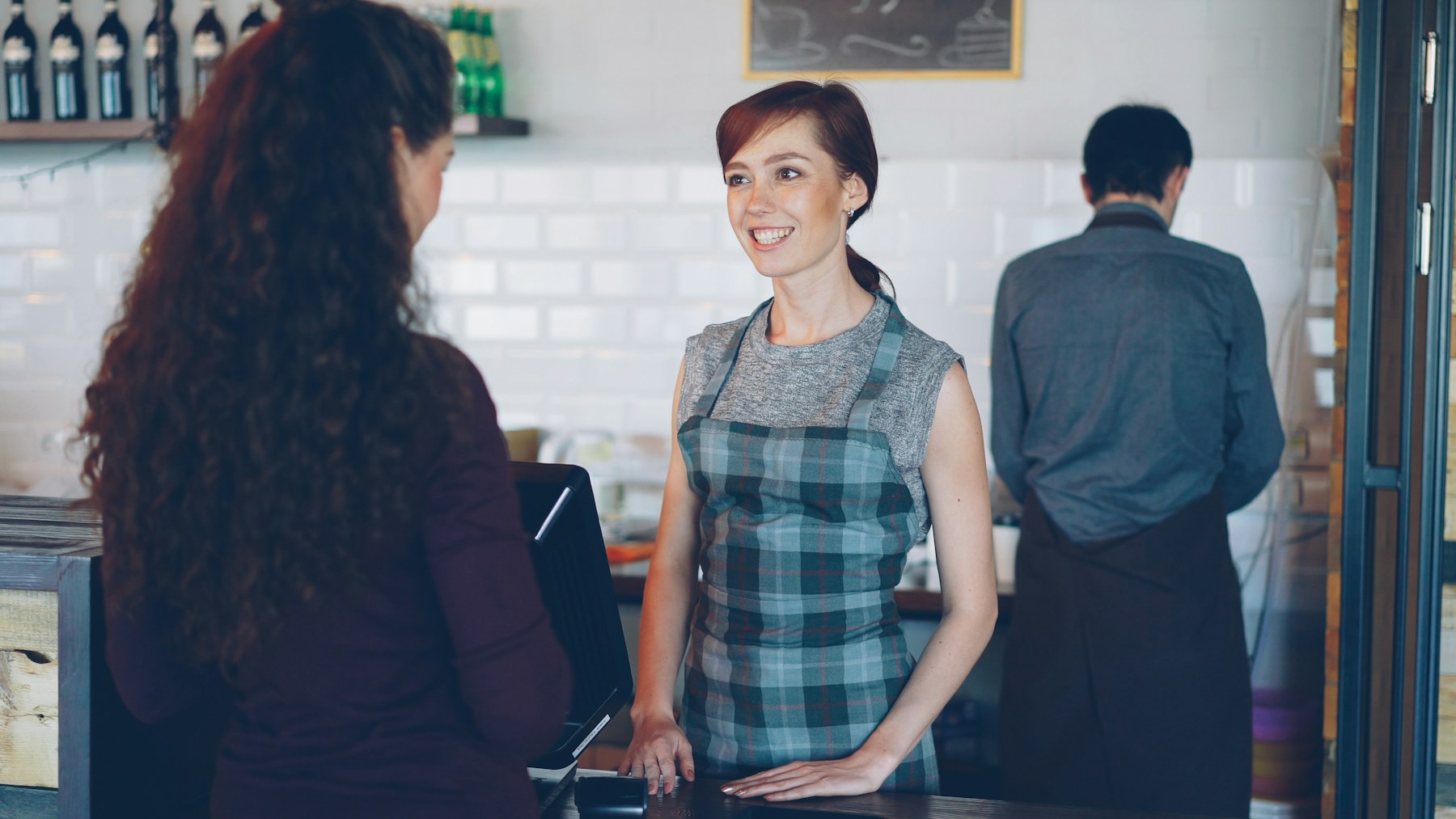 Cafe worker welcoming a customer; illustrative stock photography